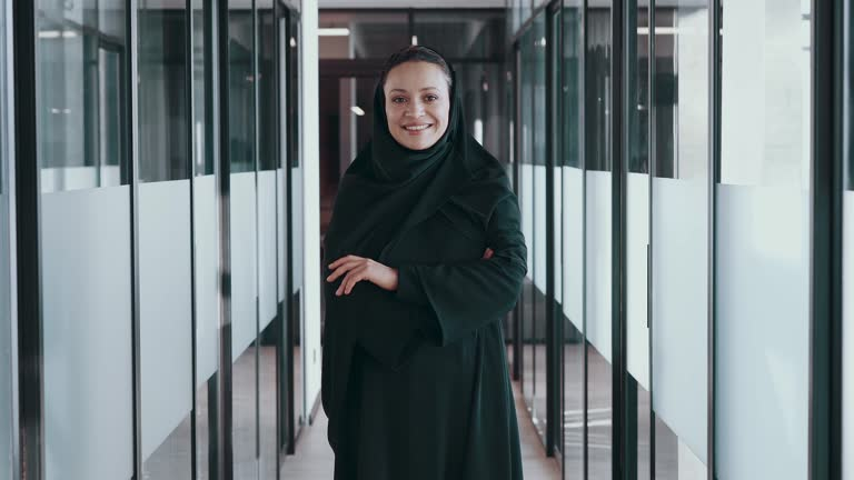 Woman in business attire standing confidently in a modern office corridor, relevant to Ajman Free Zone licensing.