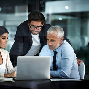 Business professionals discussing tax regulations in Dubai around a laptop in a modern office.