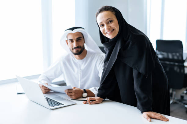 Two professionals discussing Ajman Free Zone license expenses at a business meeting with a laptop and documents.